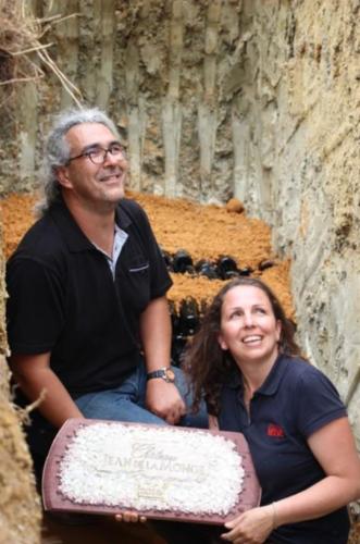 Les propriétaires du Château Jean de la Monge, tenant leur enseigne en mosaïque à l’occasion de l’ensevelissement de bouteilles spéciales 